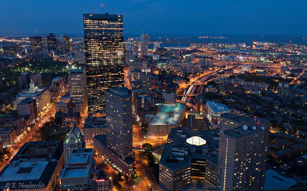 The Boston skyline at night. Michelle writes about the qualities of cities that make her feel alive and less alone — especially when she just gazes out from her balcony. COURTESY OF EMMANUEL HUYBRECHTS VIA WIKIMEDIA COMMONS

