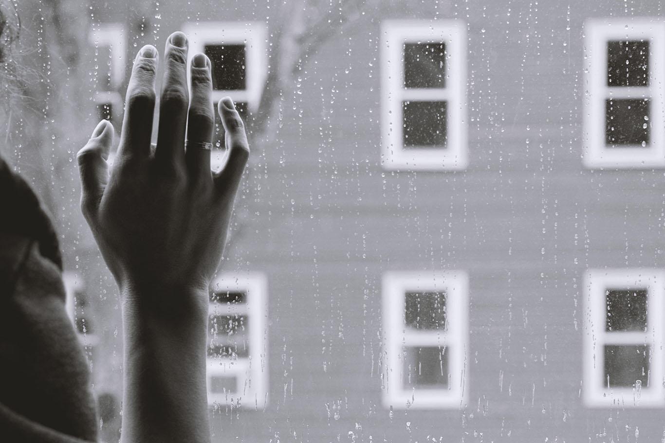 A person peering out a window on a rainy day. Michelle writes about the impact and authenticity of sad endings in stories and why she prefers them to happy ones. COURTESY OF KRISTINA TRIPKOVIC VIA UNSPLASH