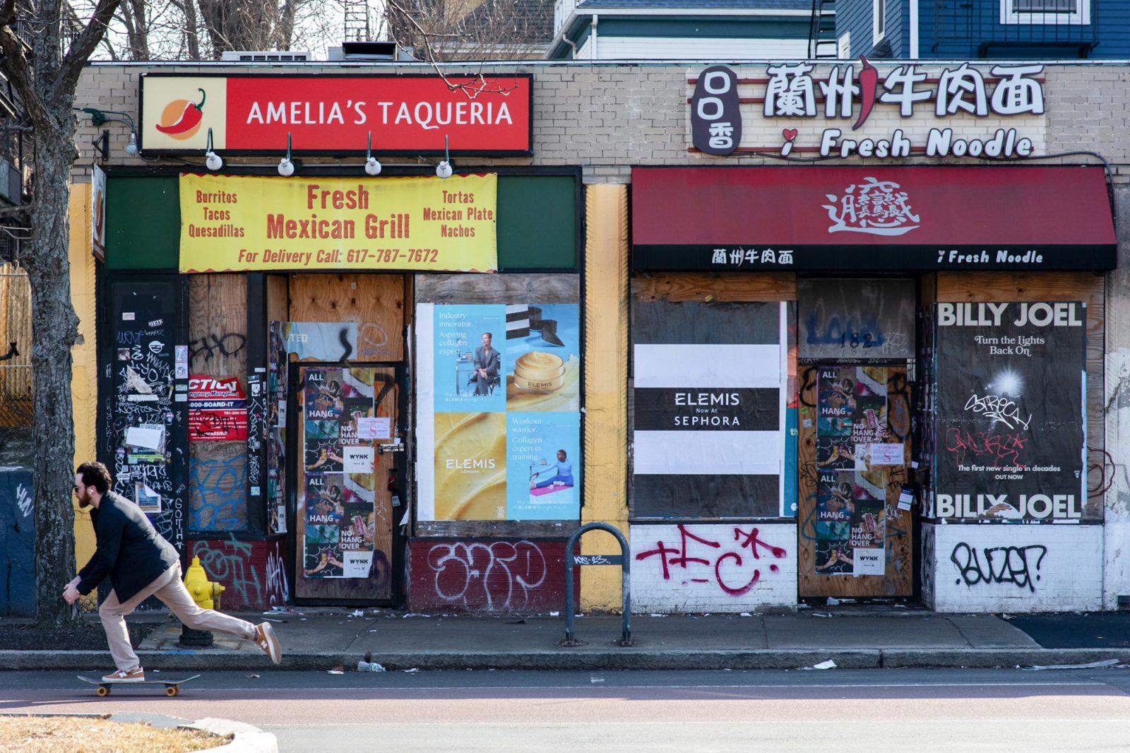 Wood planks cover the entrance to Amelia’s Taqueria and Fresh Noodles in Allston. The restaurants along 180-184 Brighton Ave have not reopened after a Sept. 2022 fire that damaged the buildings. SYDNEY ROTH/DFP PHOTOGRAPHER