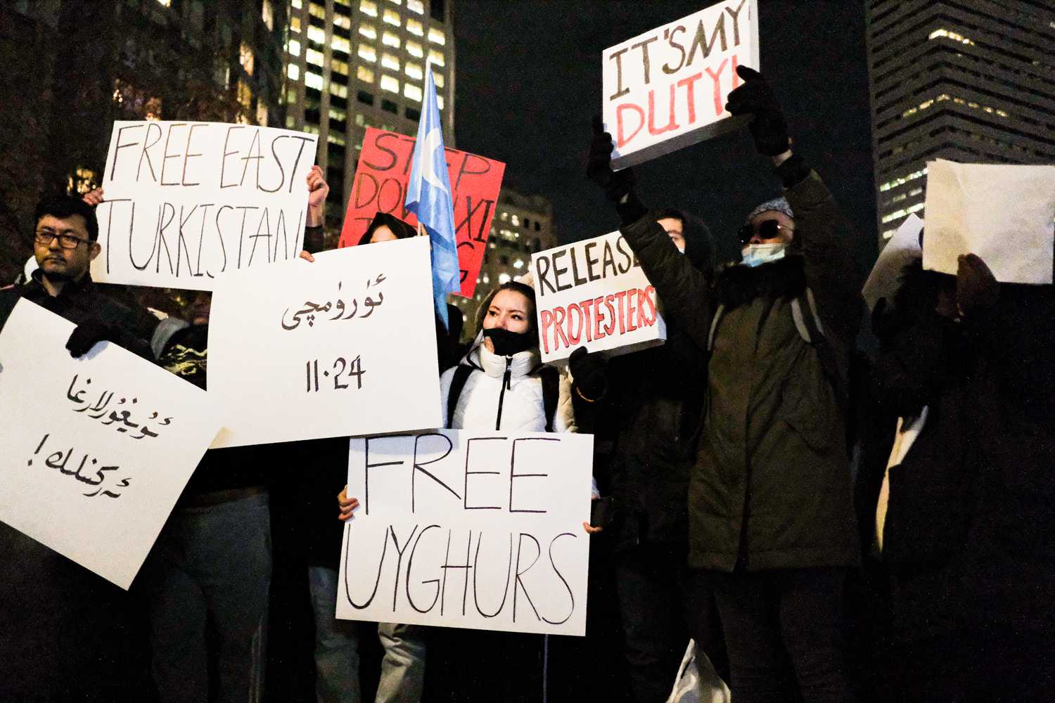 Protesters at the vigil holding signs in support of the groups affected by the Urumqi fire and China’s strict Covid policies. JULIAN ZHU/DFP STAFF
