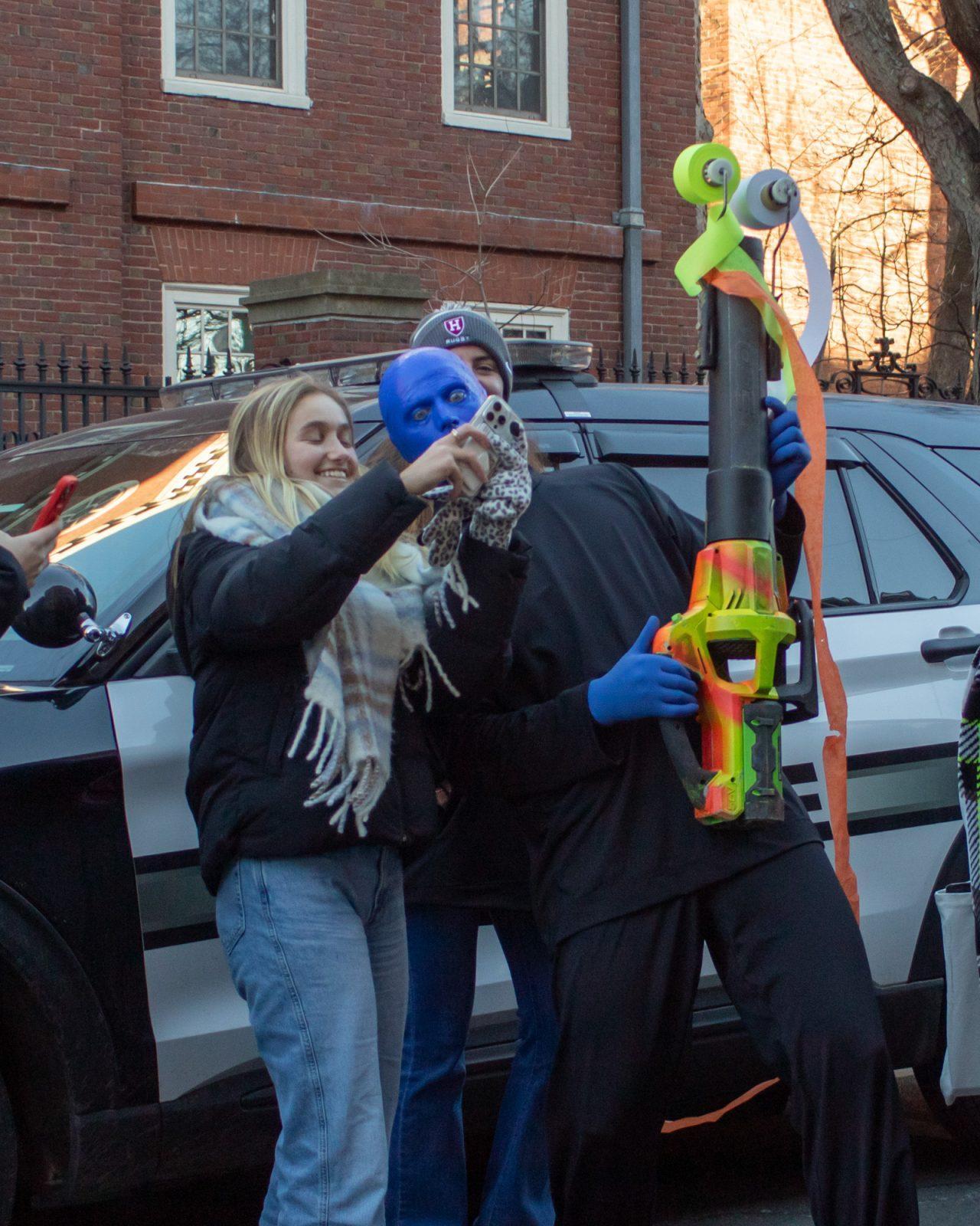 A parade attendee takes a photo with a member of the Blue Man Group. HOLLY GUSTAVSEN/DFP PHOTOGRAPHER 
