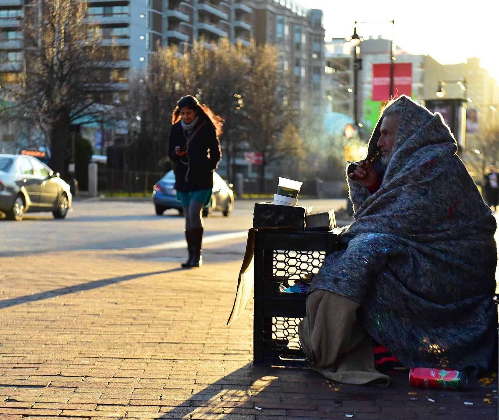 A homeless man sits wrapped in a blanket in Kenmore Square. The Massachusetts Senate passed a bill Thursday to make it easier for homeless people to obtain state IDs by eliminating fees and accepting alternative forms of residency documentation. OLIVIA FALCIGNO/ DFP FILE
