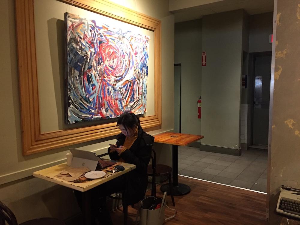 A painting hangs in Pavement Coffeehouse on Commonwealth Avenue. Artist Demetri Espinosa’s work is currently on display at Pavement. PHOTO BY VIVIAN MYRON/ DAILY FREE PRESS STAFF 

