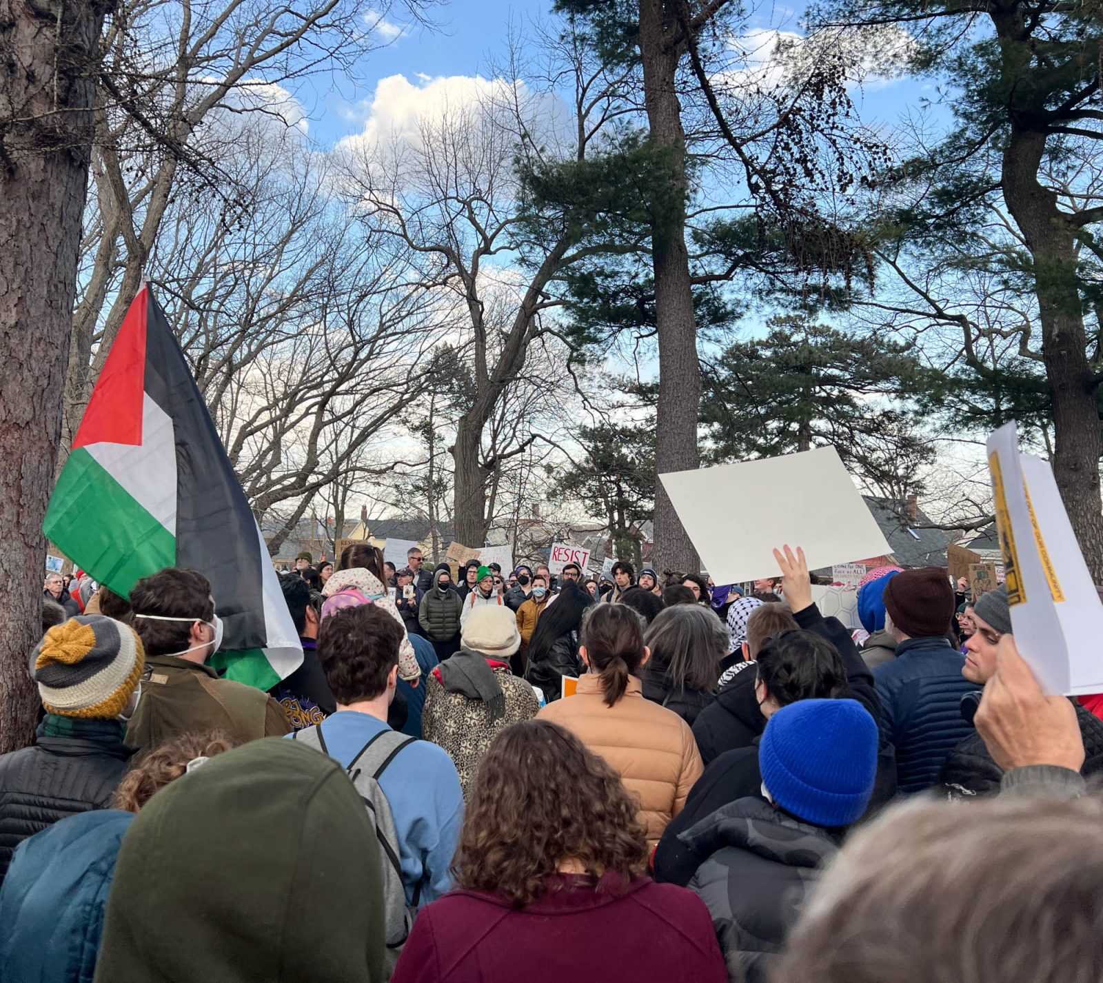 Protestors hold a Palestinian flag and signs in Somerville on Wednesday. Thousands of protestors gathered there to call for the release of a Tufts PhD student who was arrested by Federal Authorities Tuesday — the latest in a string of arrests by the Trump administration targeting international students who participated in pro-Palestine protests. PHOTO BY TRUMAN DICKERSON 