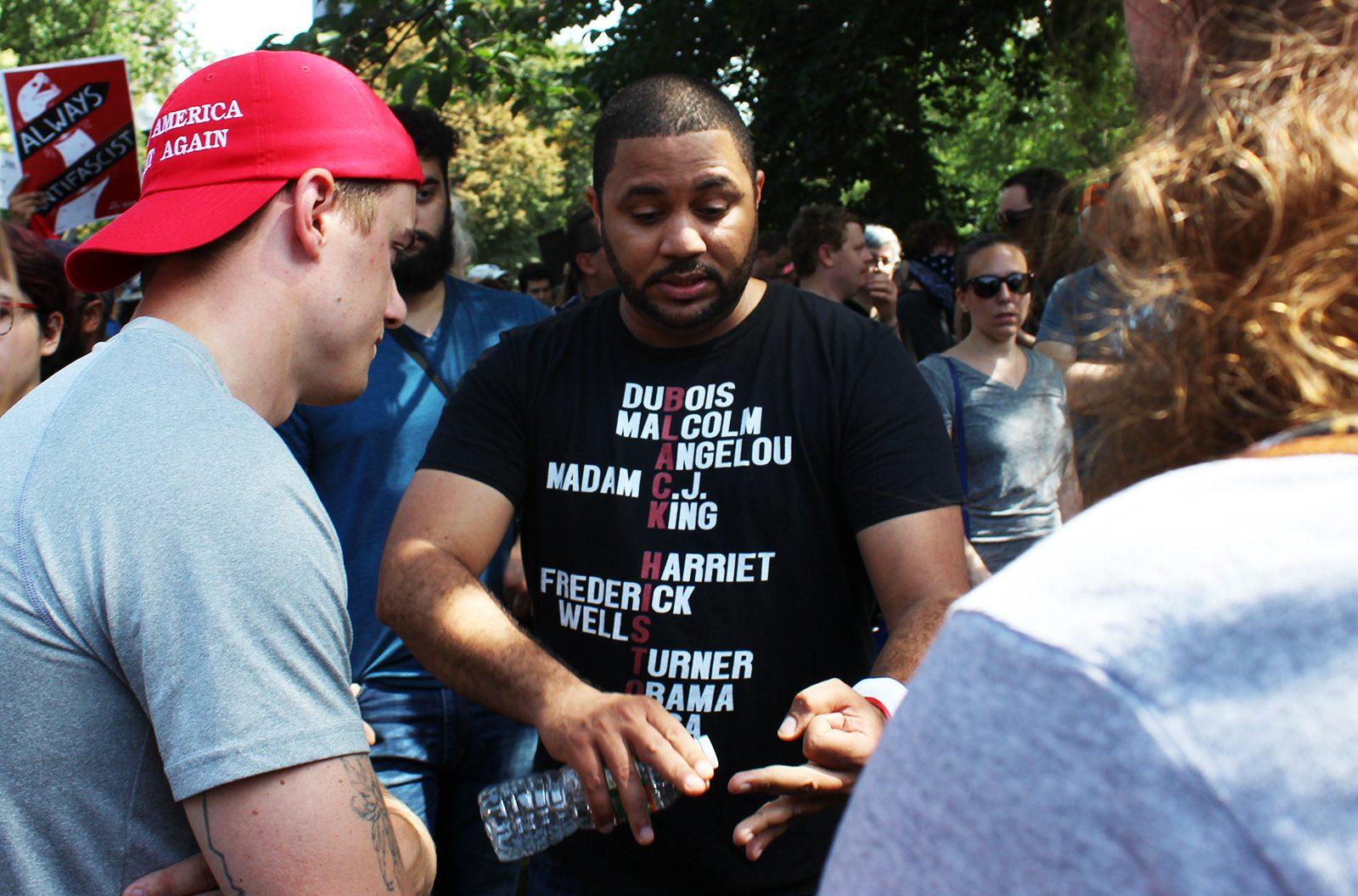 A counter-protester wearing a shirt labeled with names of black historical figures argues with a man wearing a Make America Great Again hat. PHOTO BY CARINA IMBORNONE/ DAILY FREE PRESS STAFF