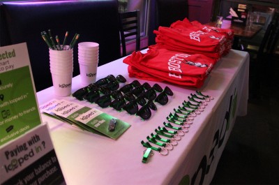 A table displays Boston University clothing and items with the Looped In logo at a semifinal Beanpot game viewing party at Sunset Cantina Tuesday evening. PHOTO BY CARLY ROSE WILLING/DAILY FREE PRESS STAFF