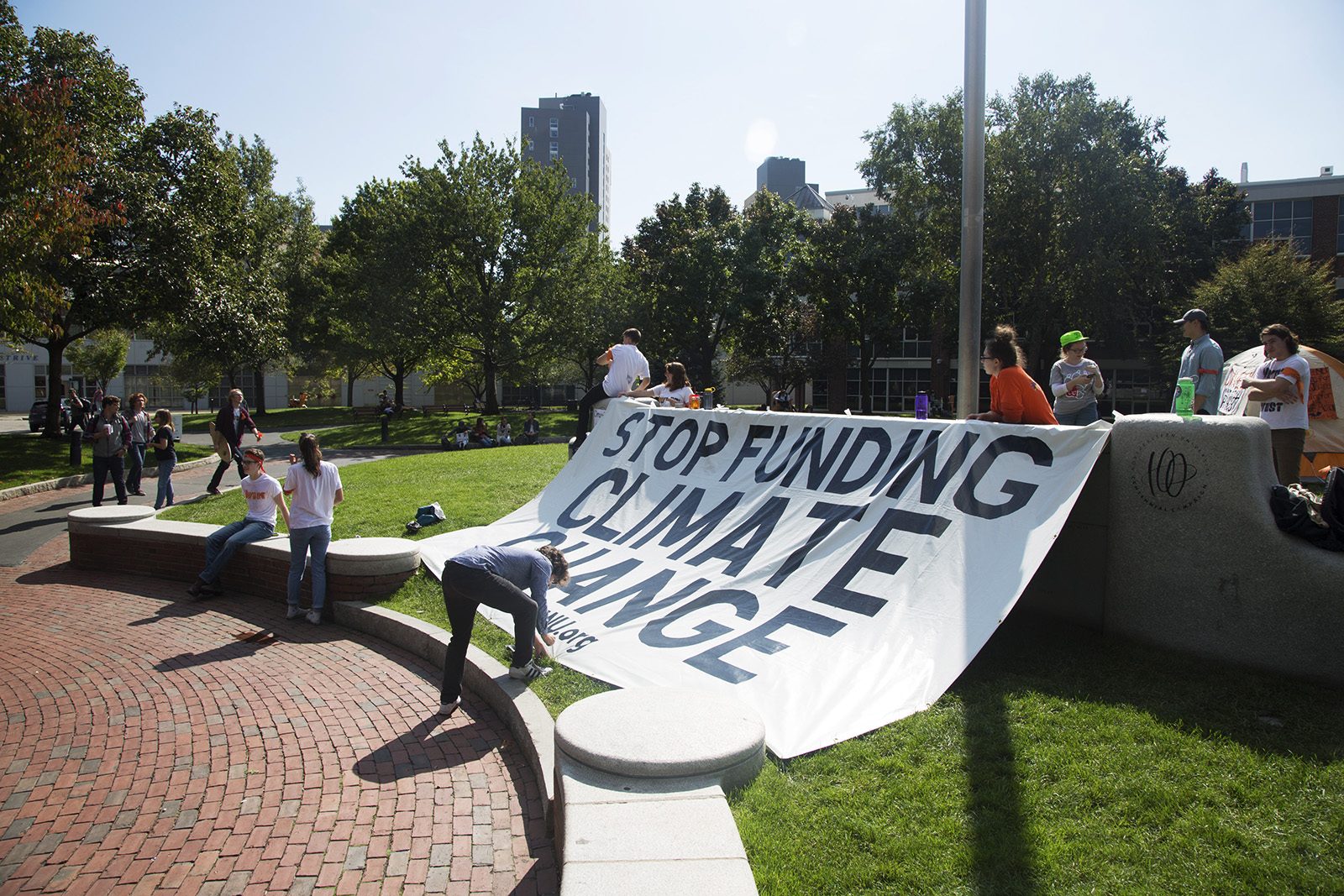 Sean Keith, a member of DivestNU, hammers in the last pin needed to hang a sign on the front wall of Centennial Common at Northeastern University. PHOTO BY NATALIE CARROLL/ DAILY FREE PRESS CONTRIBUTOR