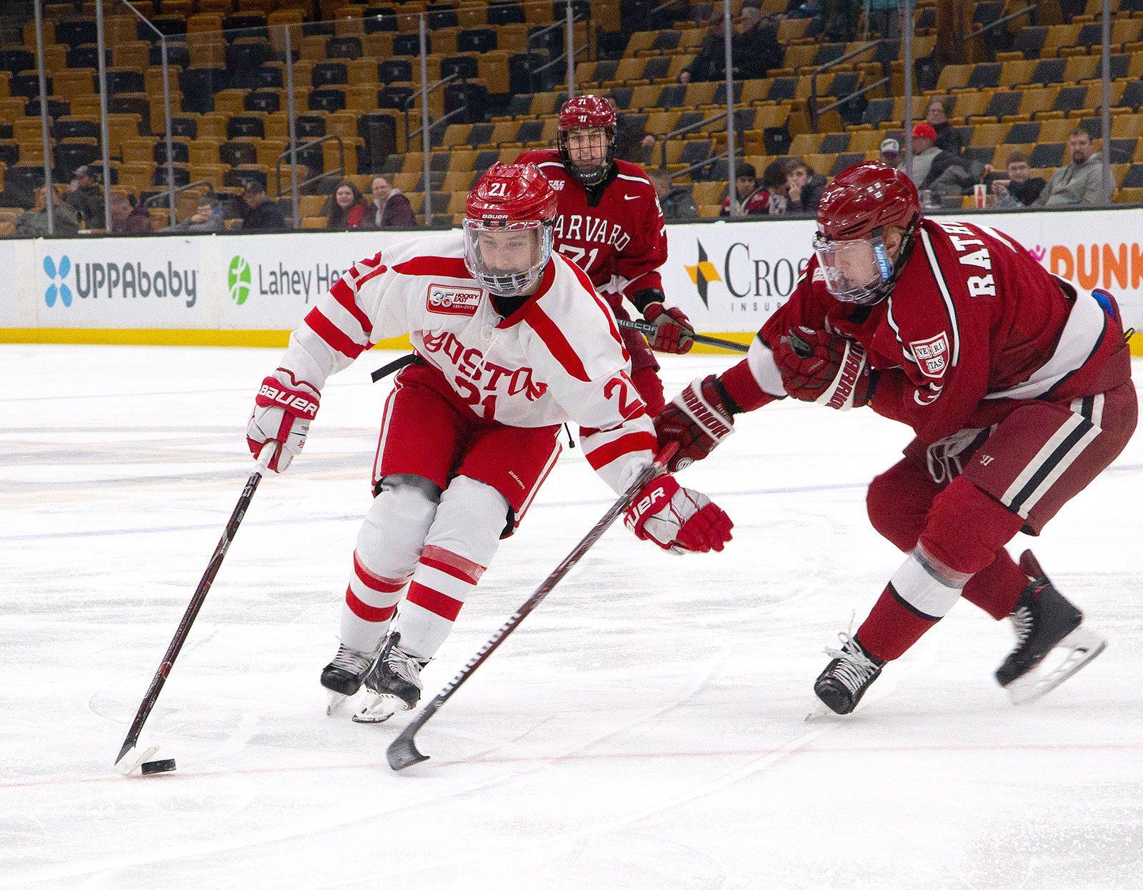 Senior forward and assistant captain Patrick Harper challenges for a loose puck (left) and shields the puck from a Harvard defenseman (right) at the TD Garden during last winter’s Beanpot tournament.