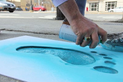 A student spray paints a footstep stencil on Commonwealth Avenue as part of the “I Will Walk With You” event hosted by the Sexual Assault Response and Prevention Center in honor of BU Sexual Assault Awareness Week. PHOTO BY OLIVIA FALCIGNO/DAILY FREE PRESS STAFF