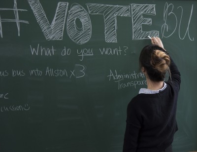 A student writes on the blackboard during a Student Government Executive Board election campaign kick-off event Monday. PHOTO BY LEXI PLINE/DAILY FREE PRESS STAFF