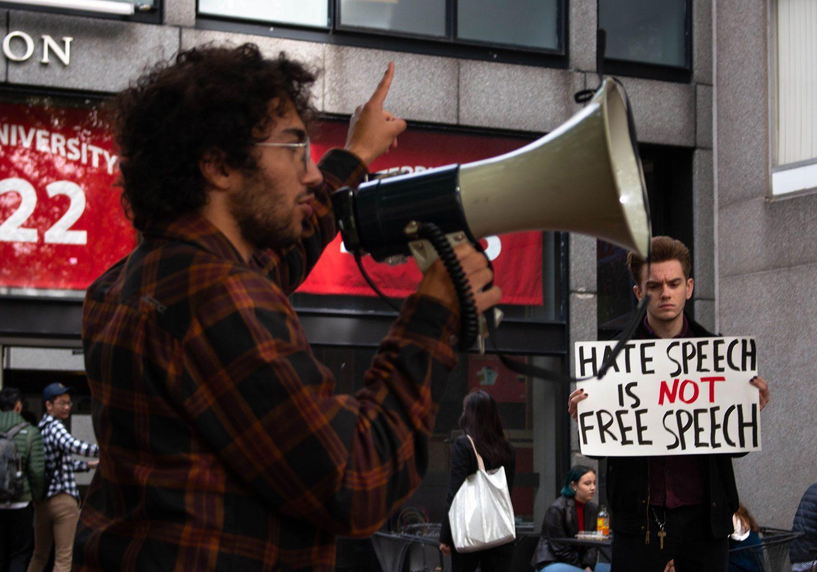 Chance Charley (CAS '21), left, speaks through a bullhorn at the crowd of students gathered in front of the George Sherman Union to protest Ben Shapiro speaking at Boston University. GABRIELA HUTCHINGS/ DAILY FREE PRESS STAFF