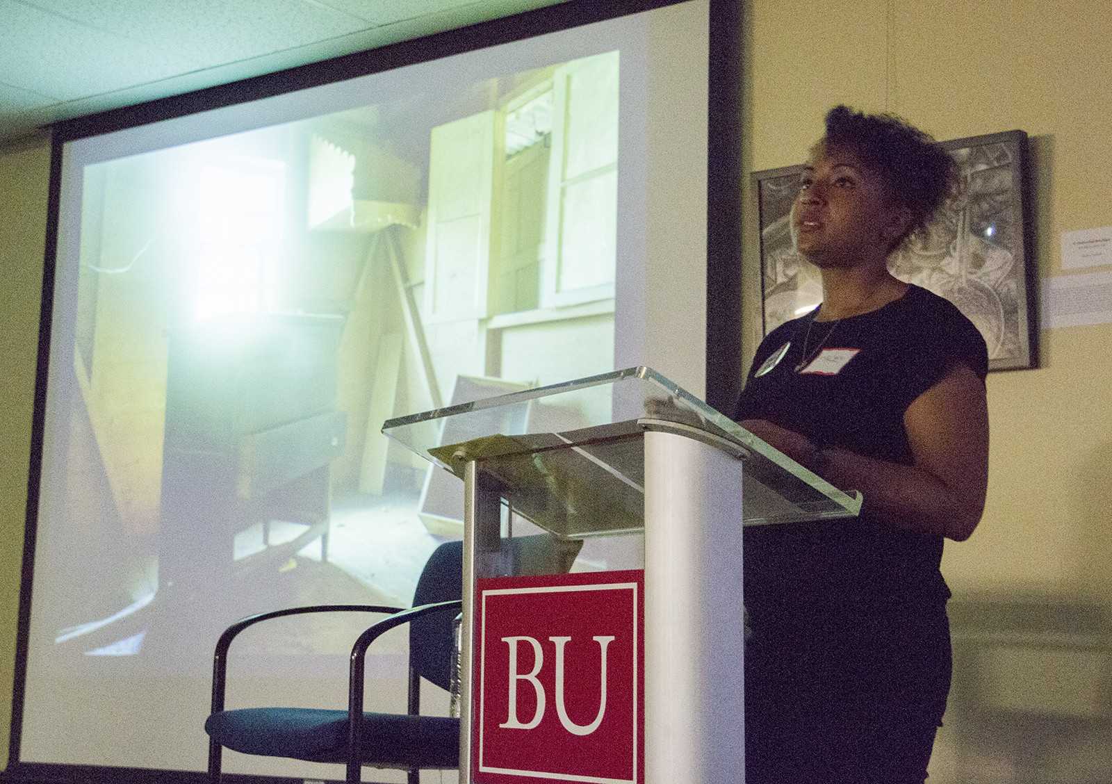 Stacey Tyrell, a photo-based artist, presents before the "Race, Identity & Art: A Forum for Student Art & Dialogue" opening reception in the Howard Thurman Center Wednesday night. PHOTO BY SARAH SILBIGER/DAILY FREE PRESS STAFF
