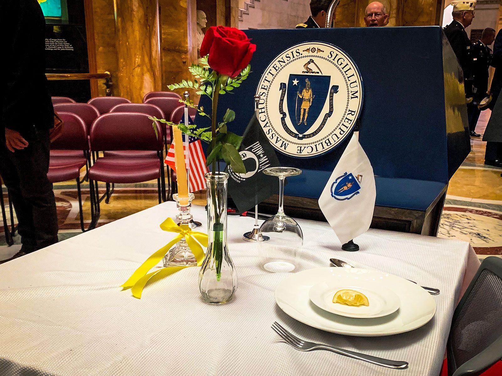 A table setting in honor of Veteran’s Day at the Massachusetts Statehouse’s Memorial Hall on Monday, decorated with symbolic elements used in a candle lighting performed by Vietnam POW Timothy Sullivan. ANGELA YANG/ DAILY FREE PRESS STAFF