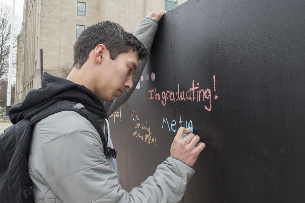 Andrew Chiao, a College of Arts and Sciences junior, writes on a chalkboard in Marsh Plaza during “Day of Remembrance.” The event was hosted by BU student group Actively Moving Forward, a college grief support network. PHOTO BY CLAIRE RICH/DAILY FREE PRESS STAFF