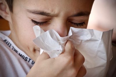 person sneezes into a tissue