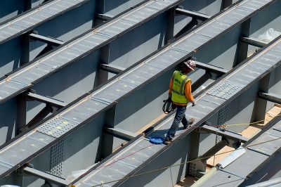 construction worker walks across a steel beam