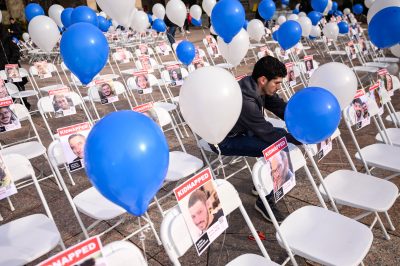 Moises Bensadon, a graduate student in the College of Engineering, ties balloons to chairs at an exhibit of empty seats representing people kidnapped by Hamas in Marsh Plaza on Dec. 1. ANDREW BURKE-STEVENSON/DFP PHOTOGRAPHER
