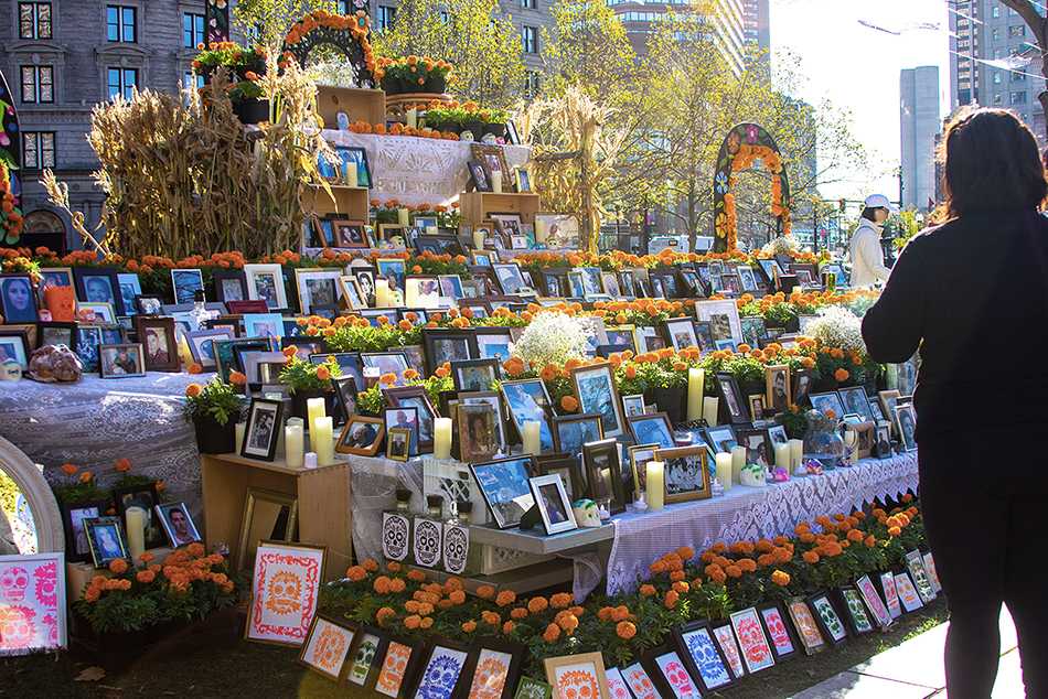A woman stands at the decorated altar placed in Copley Square in celebration of Mexican holiday Día de Muertos this past weekend. CONOR KELLEY/ DAILY FREE PRESS STAFF