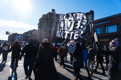 Protestor carrying a Black Lives Matter Flag at a Mass Action Against Police Brutality Protest in Boston