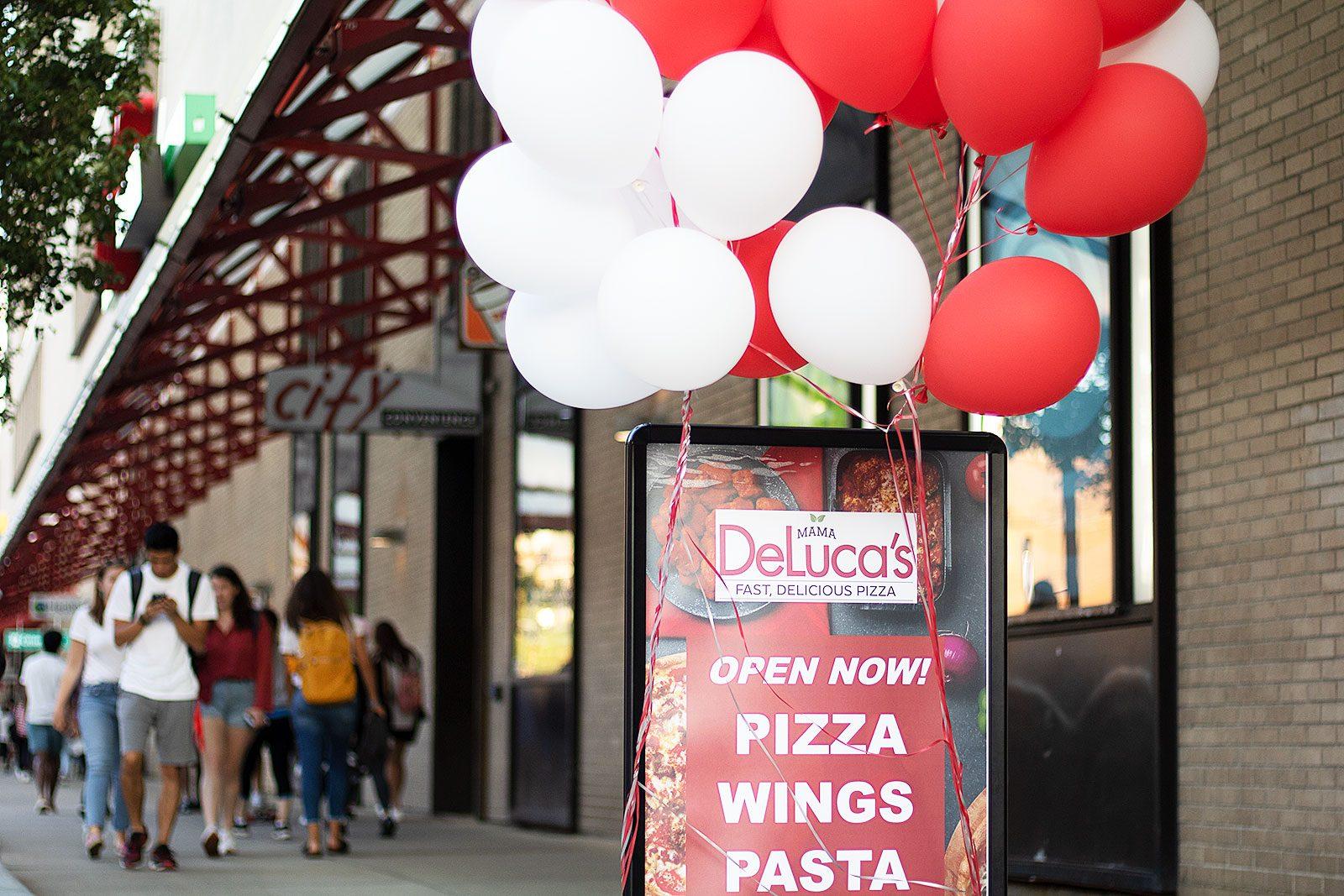 Open sign for new Mama DeLuca's location at 700 Commonwealth Ave. DeLuca's and all the other businesses in the building will now accept dining points. SOFIA KOYOMA/DAILY FREE PRESS STAFF