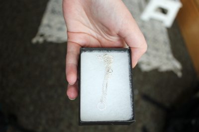 person holding a box with a necklace inside it