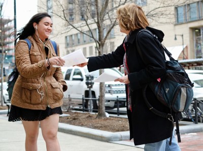 An adjunct professor hands out flyers to a student on Commonwealth Avenue during a rally before the faculty council’s spring assembly in Tsai Auditorium Wednesday afternoon. PHOTO BY SAVANAH MACDONALD/DAILY FREE PRESS STAFF