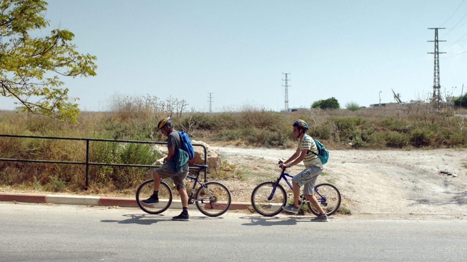 Two men ride bikes in here we are