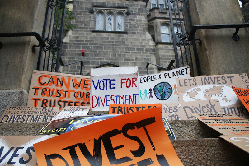 Protest signs calling on the university to divest from fossil fuels sit on the steps of the BU Castle in September 2016. BETSEY GOLDWASSER/ DFP FILE
