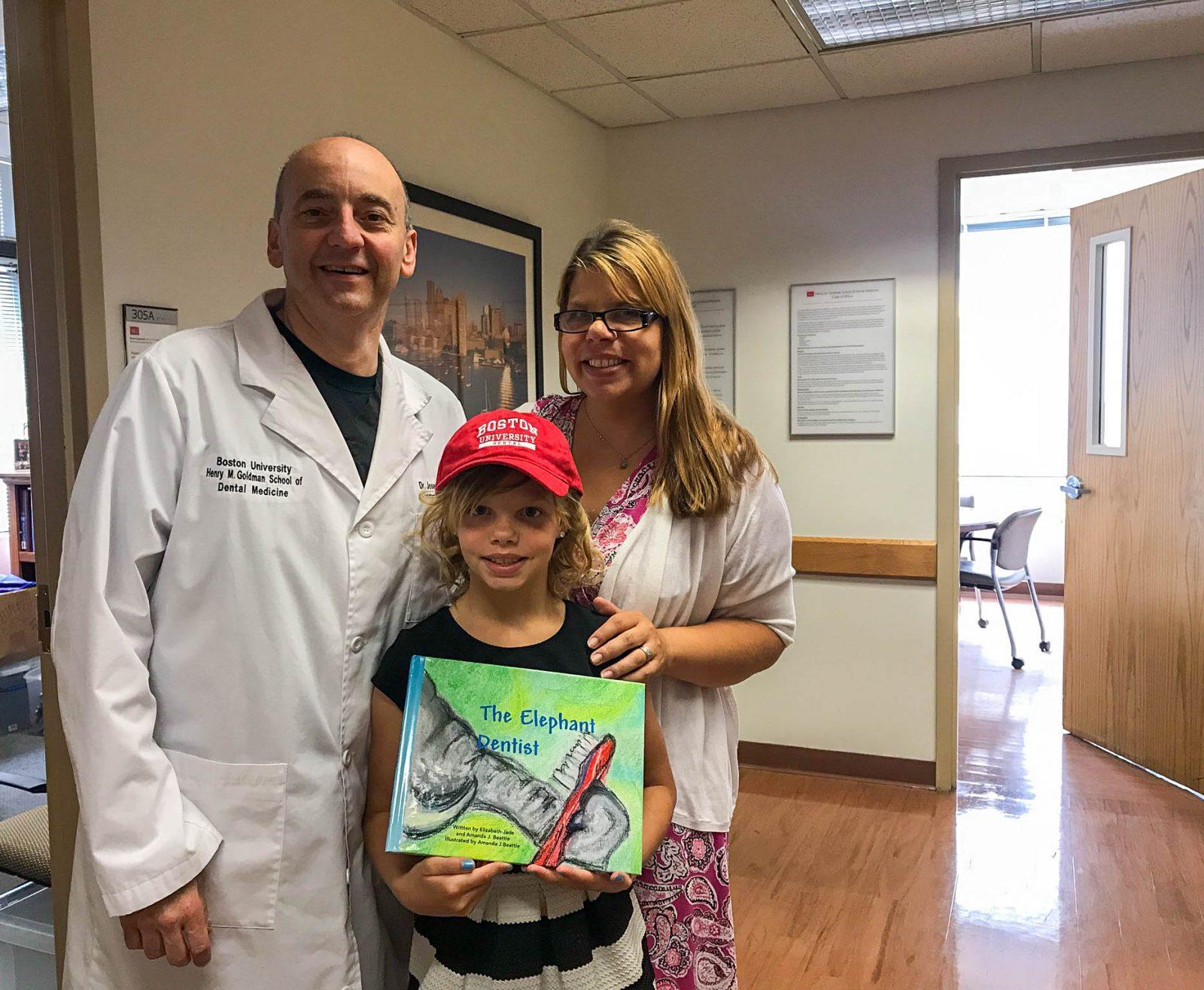 Elizabeth-Jade Beattie at a visit to Boston University to sign a book for Joseph Calabrese, associate dean of students at BU’s Henry M. Goldman School of Dental Medicine. Beattie, a 10-year-old from Beverly, published a children’s book as a tribute to her dream of someday studying at SDM. COURTESY OF AMANDA BEATTIE