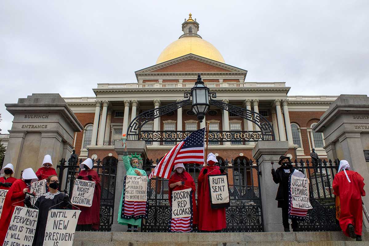 The Boston Red Cloaks, a group of women who dress as handmaids and advocate for abortion rights, gathered on the steps of the Massachusetts State House Sunday to condemn Amy Coney Barrett’s expected confirmation to the U.S. Supreme Court. SHANNON DAMIANO/ DAILY FREE PRESS STAFF


