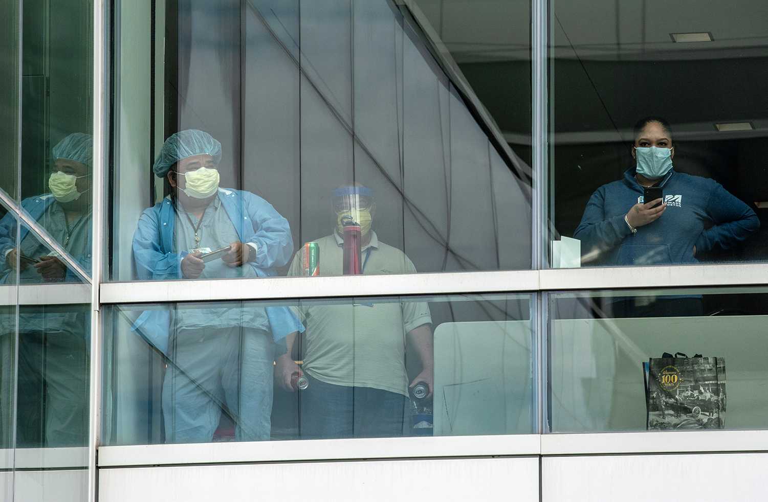 Hospital employees looked out the window of Brigham and Women’s Hospital in Longwood while fighter jets passed by in solidarity with health care workers on May 6. Brigham and Women’s Hospital identified a cluster of COVID-19 cases among both staff and patients last week. LAURYN ALLEN/ DFP FILE