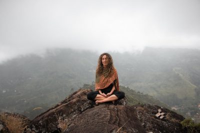 woman meditates on top of a mountain