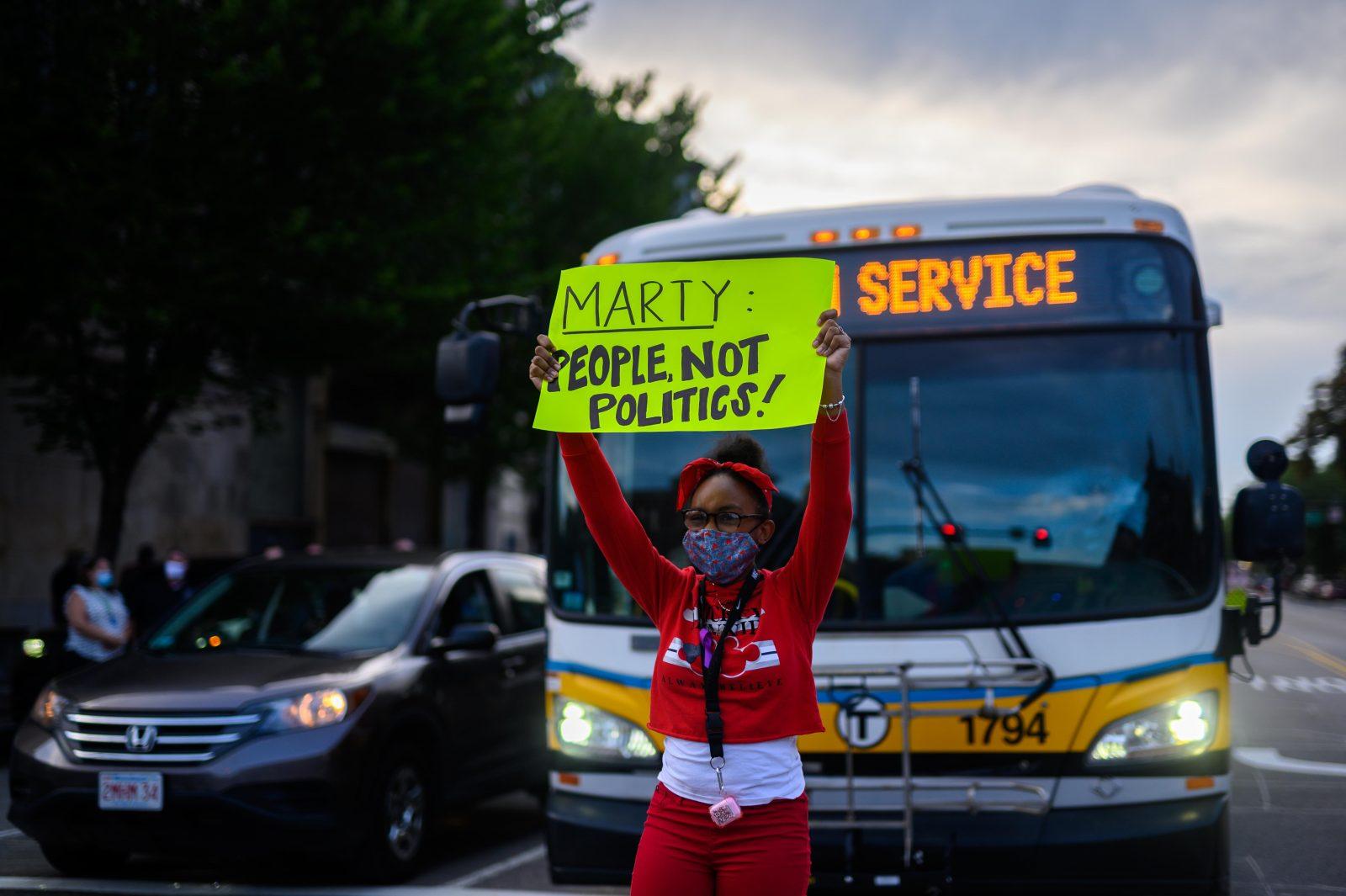 A demonstrator stands in the road at the intersection of Washington Street and Massachusetts Avenue protesting the lack of services the City offers to people facing drug addiction. LAURYN ALLEN/ DAILY FREE PRESS STAFF
