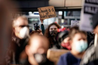 protestor holds a "chauvin is a violent criminal" sign at a minneapolis protest