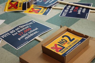Boxes of posters protesting Question 2 sit on the floor outside the William E. Reed Auditorium in Dorchester Tuesday night. PHOTO BY ABBY FREEMAN/ DAILY FREE PRESS STAFF