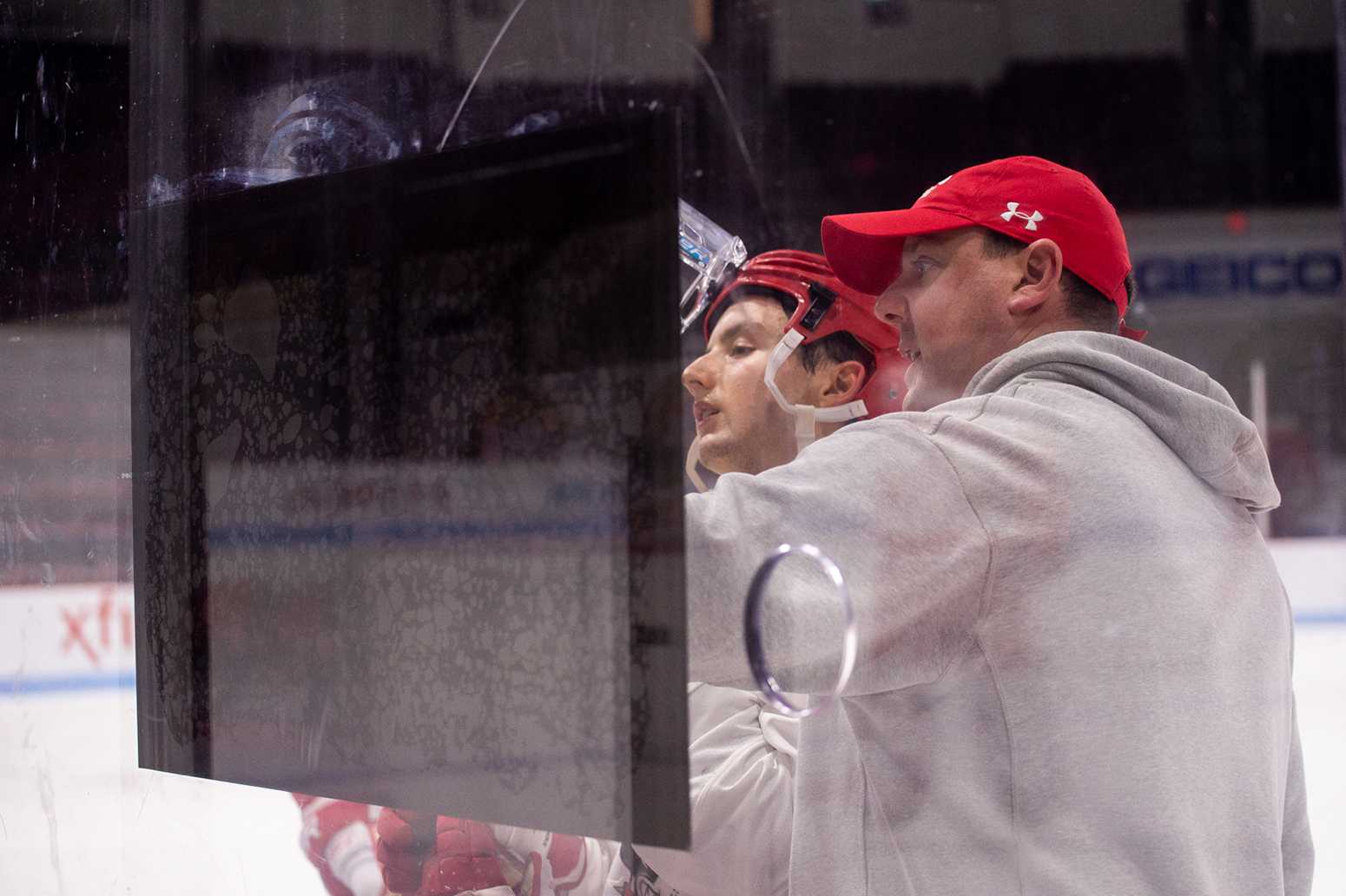 Former player and new men’s hockey coach Albie O’Connell illustrates a drill to junior forward Patrick Harper during a practice. MADDIE MALHOTRA/ DAILY FREE PRESS STAFF