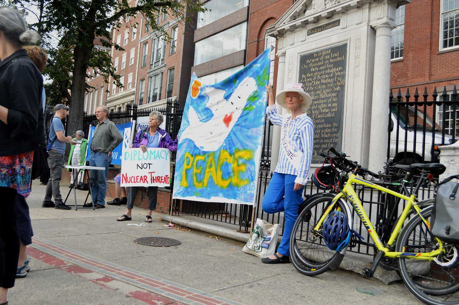 Eileen Ryan of Watertown wears her banner for peace at the Emergency Rally to oppose war in North Korea at Park Street Station Friday afternoon. PHOTO BY CAROLYN KOMATSOULIS/ DAILY FREE PRESS STAFF