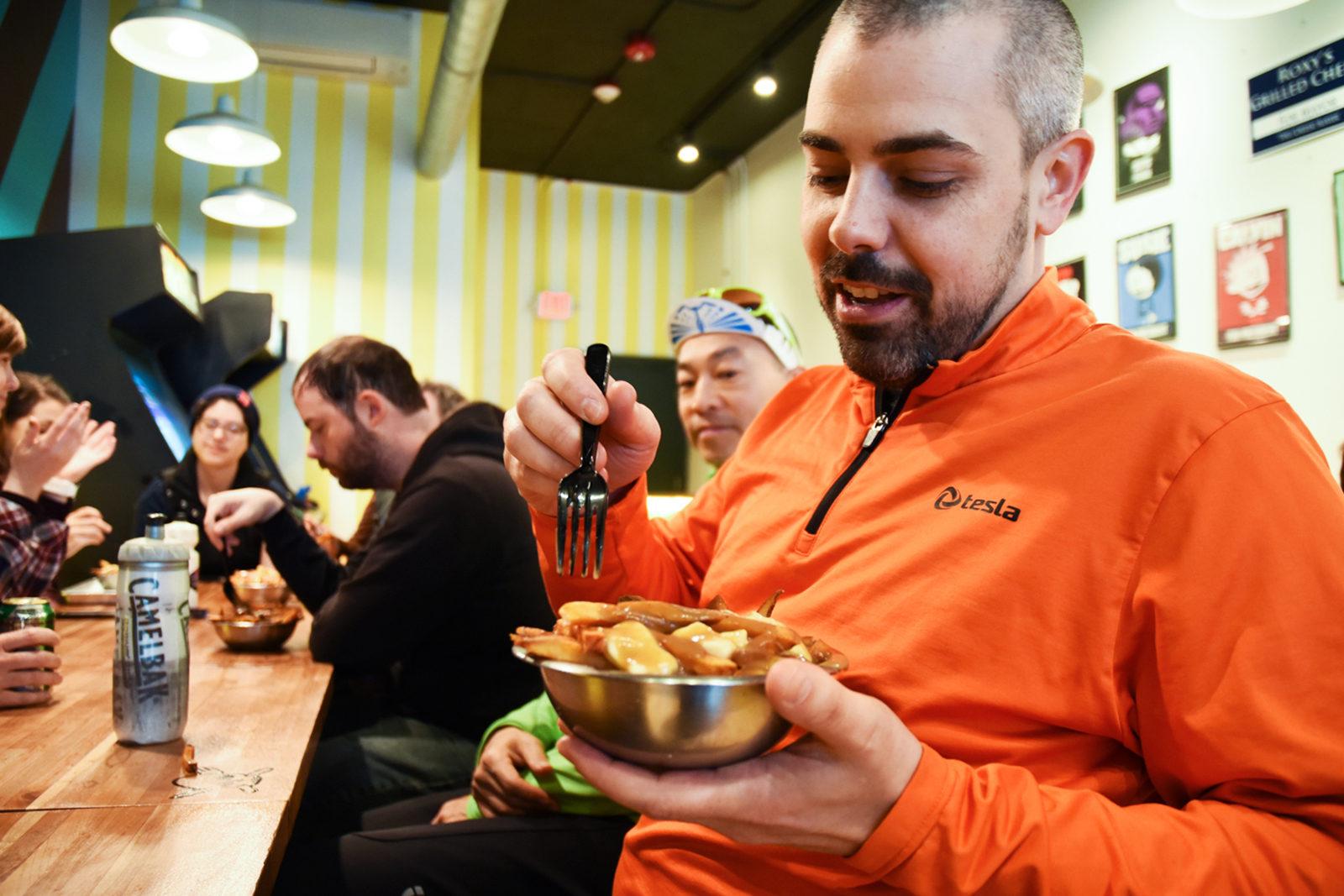 Jon Ramos, organizer of the “Gravy Train!” bike tour, digs in to his first bowl of poutine at Roxy's Grilled Cheese in Allston. PHOTO BY CHLOE GRINBERG/ DAILY FREE PRESS STAFF