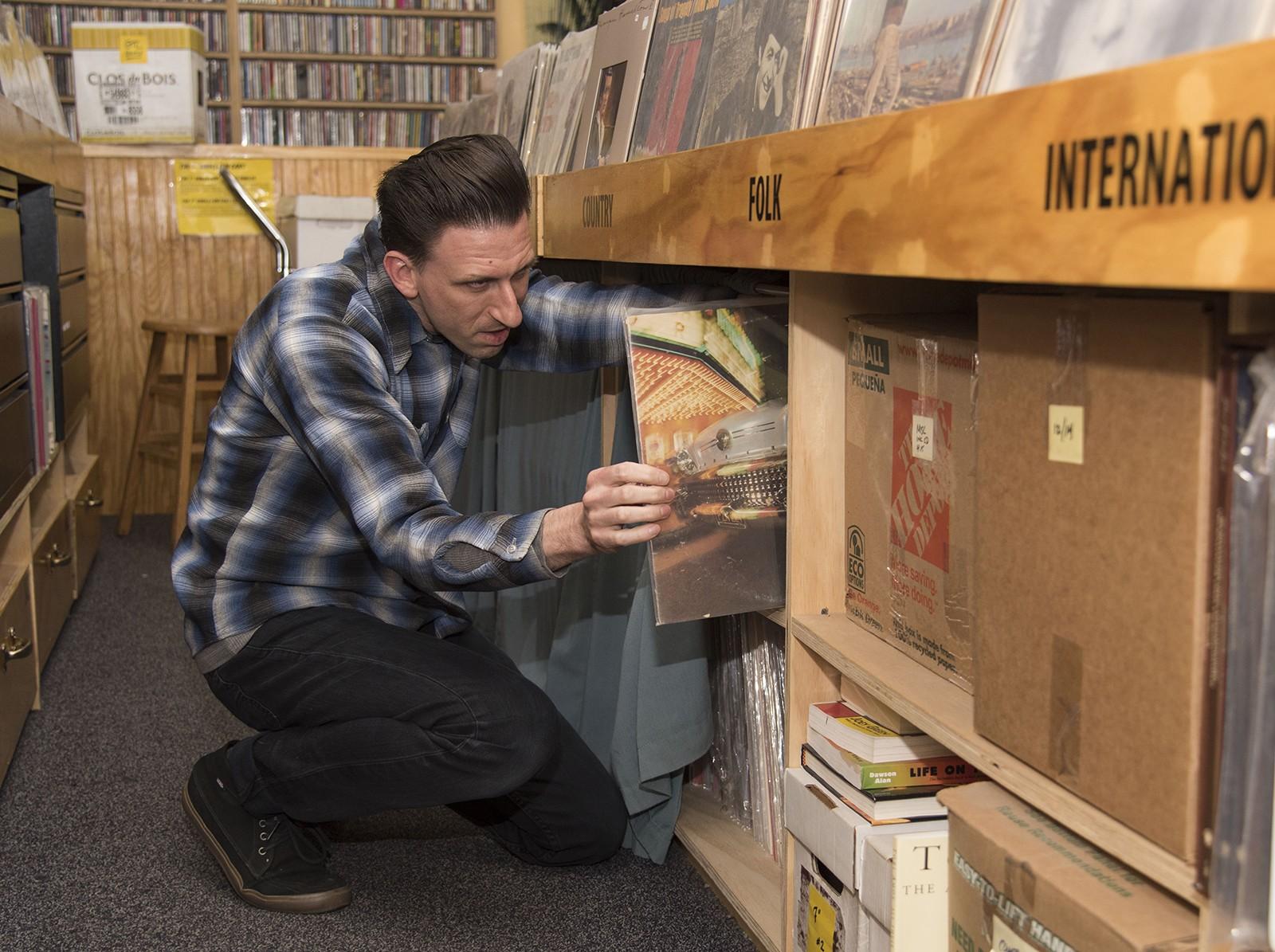 Planet Records store clerk Michael Boudreau, of Watertown, organizes vintage vinyl records Wednesday afternoon. PHOTO BY LEXI PLINE/DAILY FREE PRESS STAFF