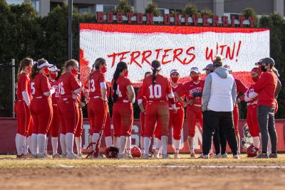 boston university softball team in front of a terriers win sign