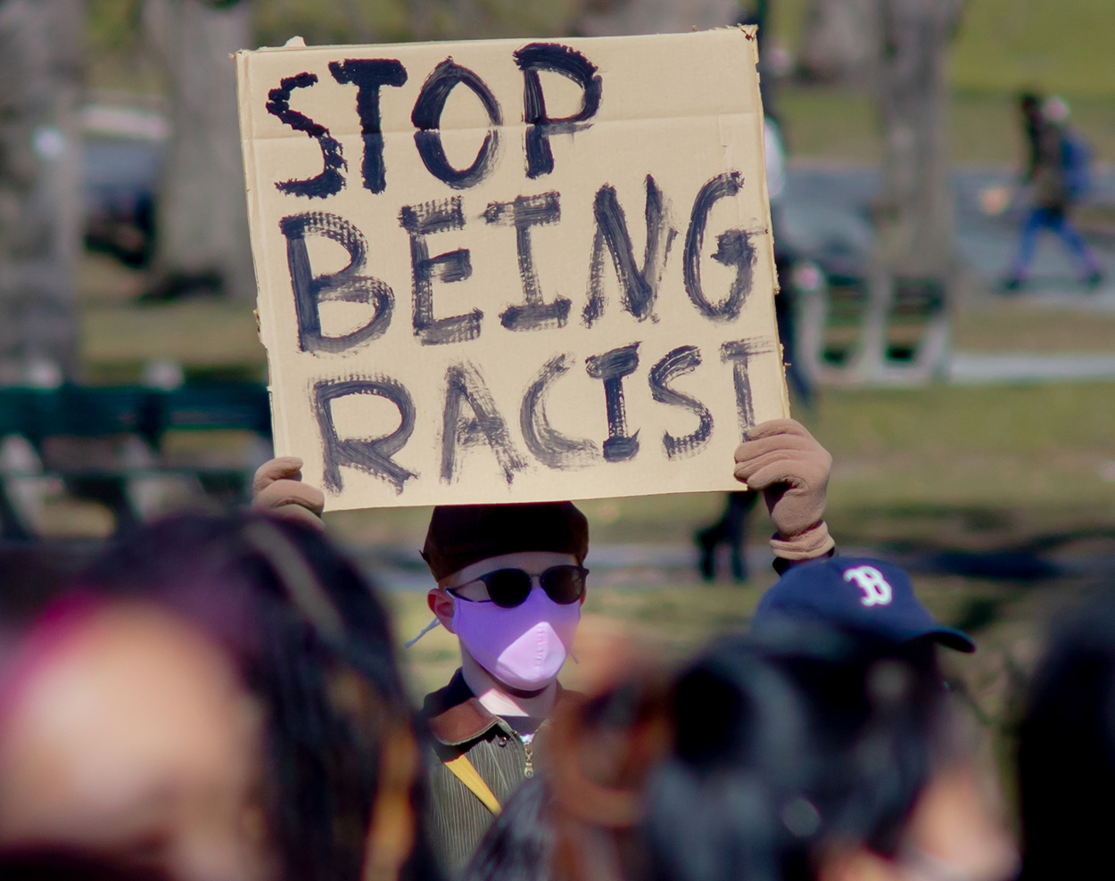 demonstrator holding a stop being racist sign at a stop asian hate protest in boston common