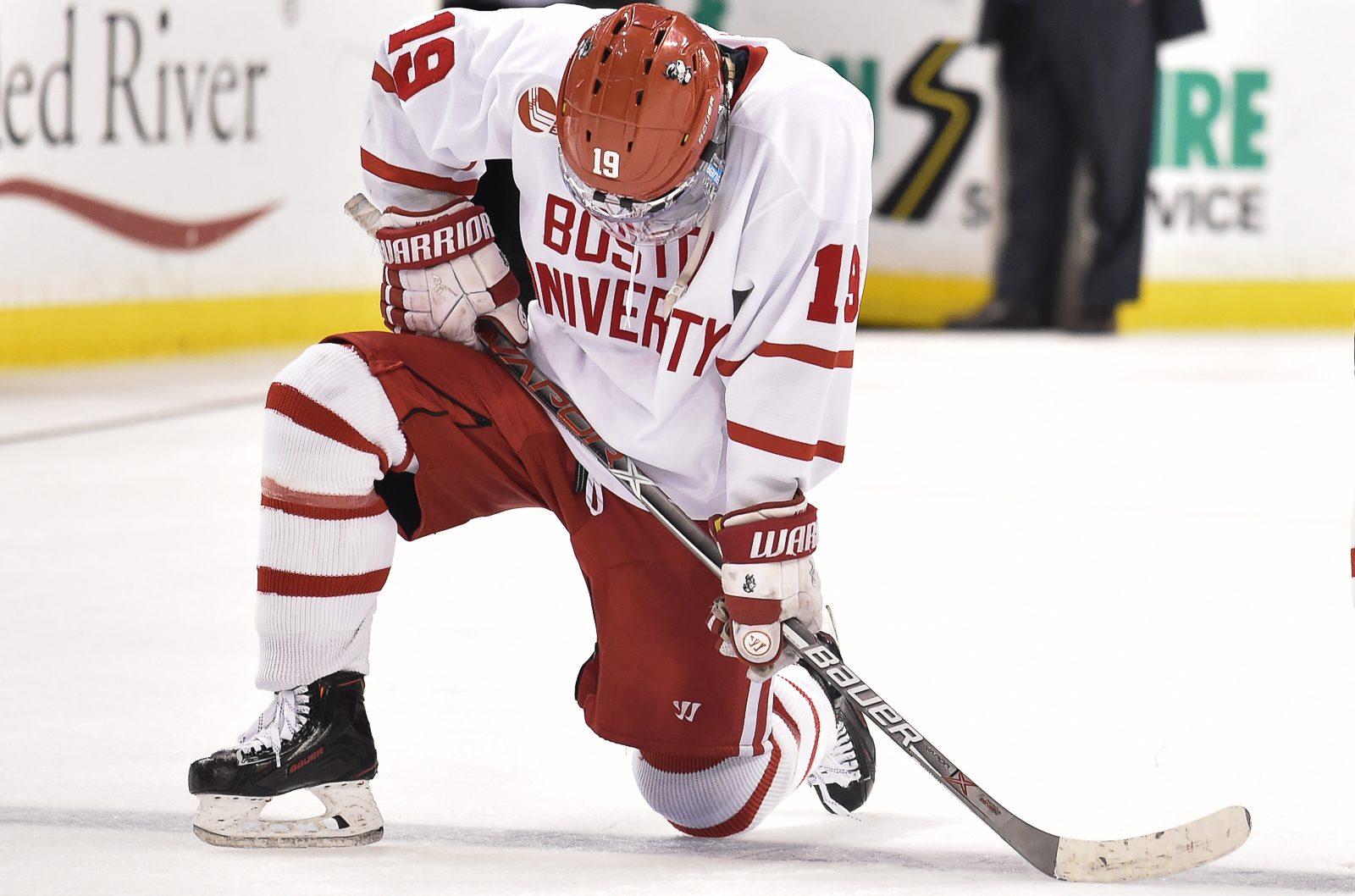 Freshman forward Clayton Keller kneels in disappointment while Harvard celebrates its 6-3 win in the Beanpot Championship. PHOTO BY MADDIE MALHOTRA/ DAILY FREE PRESS STAFF